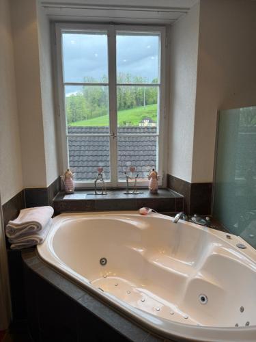 a large bath tub in a bathroom with a window at Hotel Krone Sihlbrugg in Sihlbrugg Dorf
