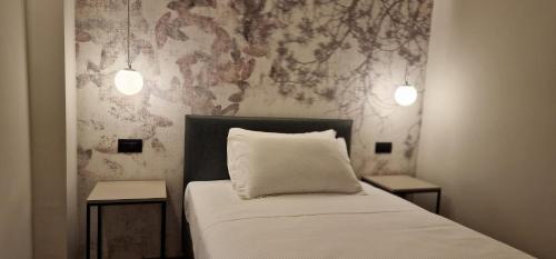 a bedroom with a bed with two side tables and two lights at Hotel La Rocca in San Marino