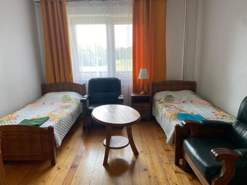 a room with two beds and a table and a chair at Agroturystyka Katarzyna Tarasiewicz in Stary Folwark