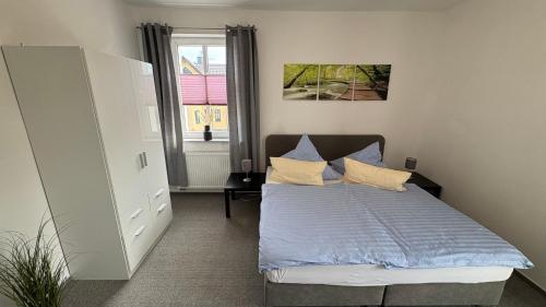 a bedroom with a bed with blue sheets and pillows at Haus am Röblinsee - Ferienwohnungen in Fürstenberg in Fürstenberg-Havel