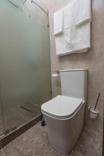 a bathroom with a toilet and a shower with towels at Kaganat Boutique Hotel in Osh