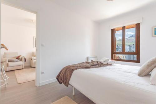 ein weißes Schlafzimmer mit einem Bett und einem Fenster in der Unterkunft Collado, terraza con vistas y garaje - Arafita Apartamentos in Formigal
