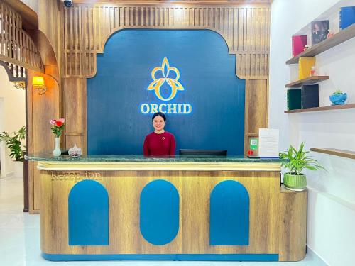 a man standing behind a counter in a office at ORCHID Hotel in Da Lat
