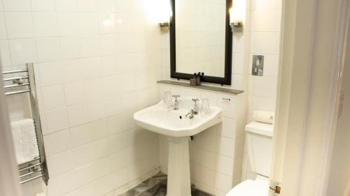 a white bathroom with a sink and a mirror at Manor House Hotel in Bishop Auckland
