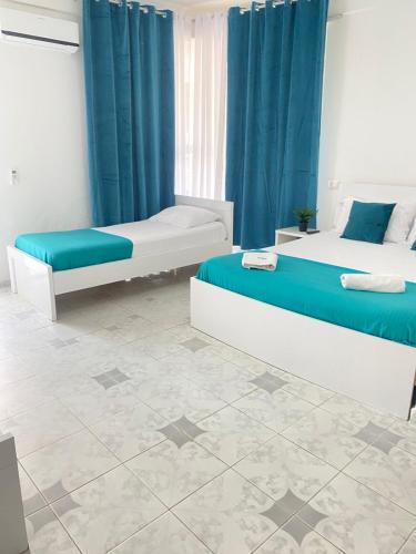 two beds in a room with blue curtains at Rai Rooms in Durrës