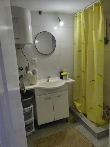 a bathroom with a sink and a yellow shower curtain at Casa Rajac - By Isak in Polom