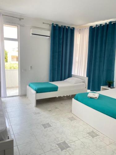 a room with two beds and blue curtains at Rai Rooms in Durrës