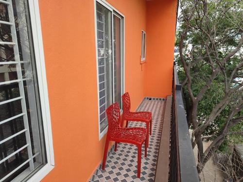 two red chairs sitting on the porch of a house at Samuels Comfort Homes in Bengaluru