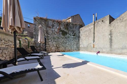 a swimming pool with two chairs and an umbrella at Holiday Home Tranquilla with heated pool in Blato
