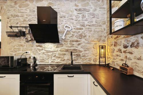a kitchen with a sink and a stone wall at Holiday Home Tranquilla with heated pool in Blato