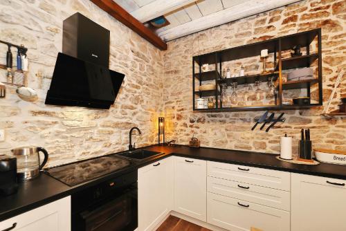 a kitchen with white cabinets and a black sink at Holiday Home Tranquilla with heated pool in Blato