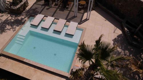 an overhead view of a swimming pool with chairs and a palm tree at Numi Suites in Mýkonos City