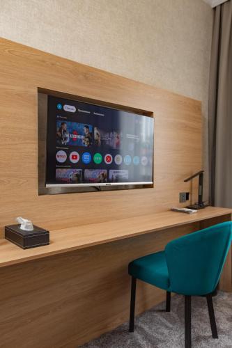 a room with a tv and a blue chair at Kaganat Boutique Hotel in Osh