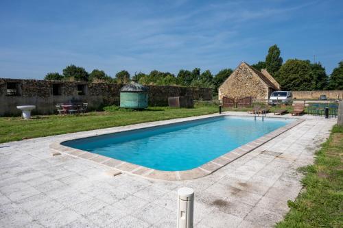una piscina in un cortile con un muro di pietra di Manoir du Bois Joly - Roulotte Vintage a Margon