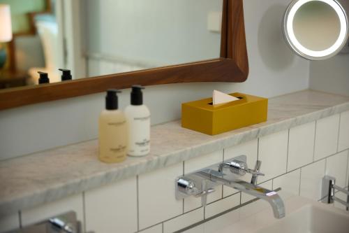 a bathroom counter with two bottles of soap and a mirror at The July - Twenty Eight in Amsterdam