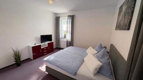 a bedroom with a bed and a television in it at Haus am Röblinsee - Ferienwohnungen in Fürstenberg in Fürstenberg-Havel