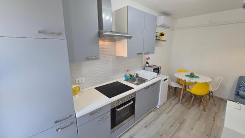 a kitchen with white cabinets and a small table at Lennida Studio Apartman with free parking in Kavran