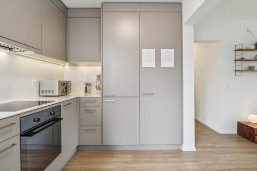 a white kitchen with white cabinets and appliances at UP&GREAT Apartments - Chic Urban Homes in Zürich