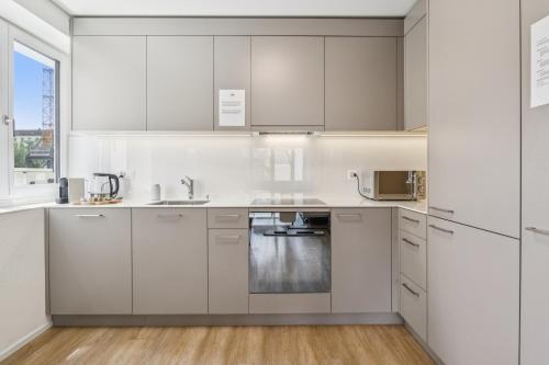 a kitchen with white cabinets and a sink at UP&GREAT Apartments - Chic Urban Homes in Zürich