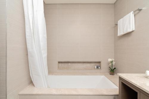 a white bathroom with a tub and a sink at Grande, Luxurious 2 BR, Burj Khalifa & Fountain view in Dubai