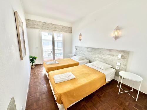 two beds in a small room with wooden floors at Apartamento com vista mar no centro antigo in Bicas