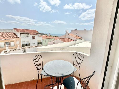 a table and chairs on a balcony with a view at Apartamento com vista mar no centro antigo in Bicas