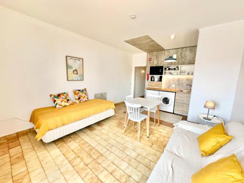 a bedroom with two beds and a table and a kitchen at Apartamento com vista mar no centro antigo in Bicas
