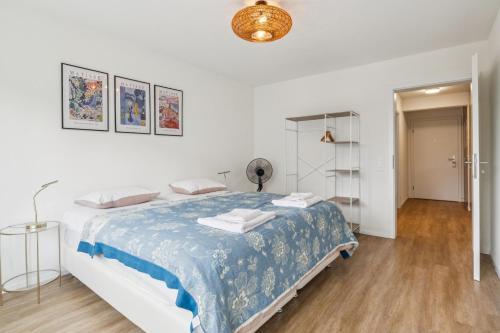 a white bedroom with a bed with a blue blanket at UP&GREAT Apartments - Chic Urban Homes in Zürich