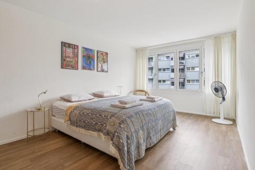 a white bedroom with a bed and a window at UP&GREAT Apartments - Chic Urban Homes in Zürich