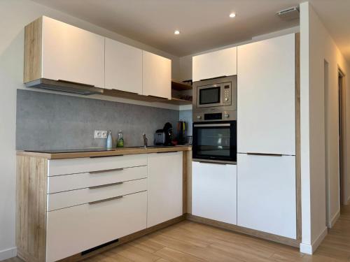 une cuisine avec des armoires blanches et un micro-ondes dans l'établissement Appartement les pieds dans l'eau Saint Cyprien, à Saint-Cyprien