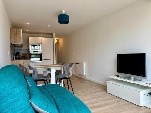 ein Wohnzimmer mit einer Couch, einem Fernseher und einem Tisch in der Unterkunft Appartement les pieds dans l'eau Saint Cyprien in Saint-Cyprien