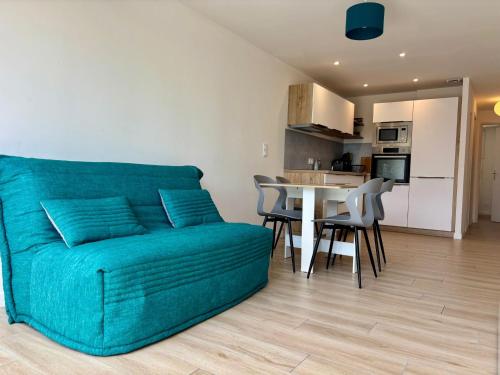 ein Wohnzimmer mit einer Couch und einem Tisch mit Stühlen in der Unterkunft Appartement les pieds dans l'eau Saint Cyprien in Saint-Cyprien