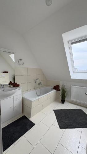 a white bathroom with a tub and a sink at Haus am Röblinsee - Ferienwohnungen in Fürstenberg in Fürstenberg-Havel