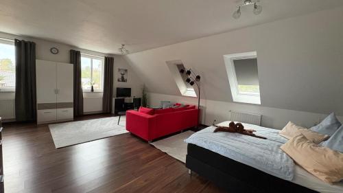 a living room with a bed and a red couch at Haus am Röblinsee - Ferienwohnungen in Fürstenberg in Fürstenberg-Havel