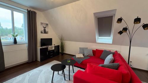 a living room with a red couch and a table at Haus am Röblinsee - Ferienwohnungen in Fürstenberg in Fürstenberg-Havel