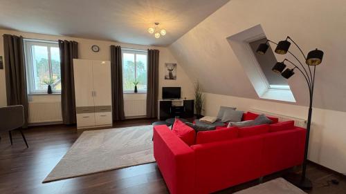 a living room with a red couch and some windows at Haus am Röblinsee - Ferienwohnungen in Fürstenberg in Fürstenberg-Havel