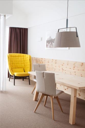 a dining room with a table and yellow chair at Hotel Cristal in Obereggen