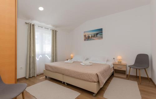 een witte slaapkamer met een bed en 2 stoelen bij Villa Primabella -Makarska by Villas Guide in Novak