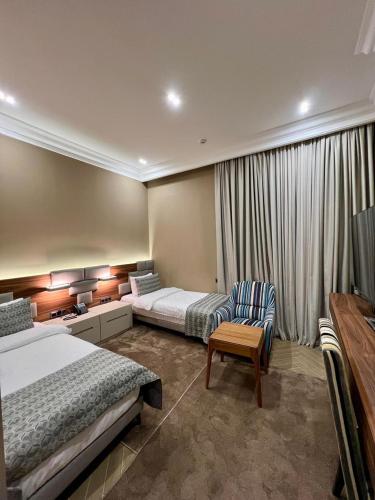 a hotel room with two beds and a chair at Plaza Viktoria Hotel Yerevan in Yerevan