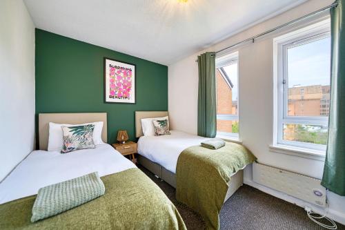 Dos camas en una habitación con paredes y ventanas verdes. en 2BR City Flat Walk to Buchanan Hydro with Parking, en Glasgow