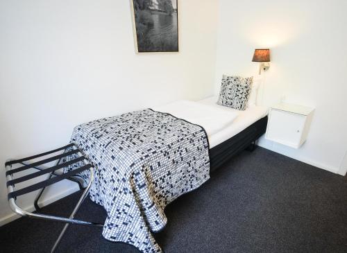 a bedroom with a bed with a blanket and a chair at Golf Hotel Viborg in Viborg