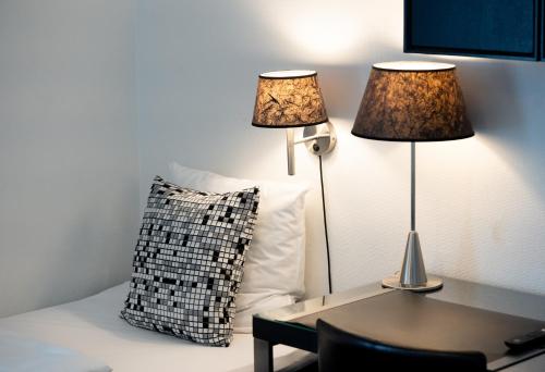 two lamps on a bed with a pillow and a table at Golf Hotel Viborg in Viborg