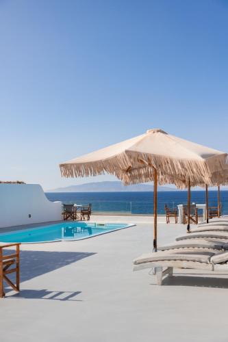 a beach with chairs and umbrellas and a swimming pool at Vrachia Studios & Apartments in Oia