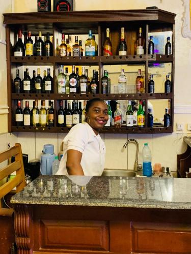 a woman standing behind a counter in a bar at DF HÔTEL Plazza in Yaoundé