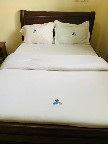 a bed with white sheets and pillows in a room at DF HÔTEL Plazza in Yaoundé