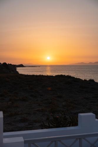 a sunset over the ocean with a white fence at Vrachia Studios & Apartments in Oia