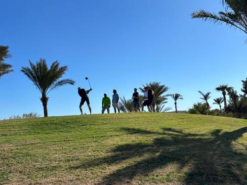 a group of people playing golf on a hill with palm trees at Pickalbatros Golf Luxury Suites - All Inclusive in Sharm El Sheikh