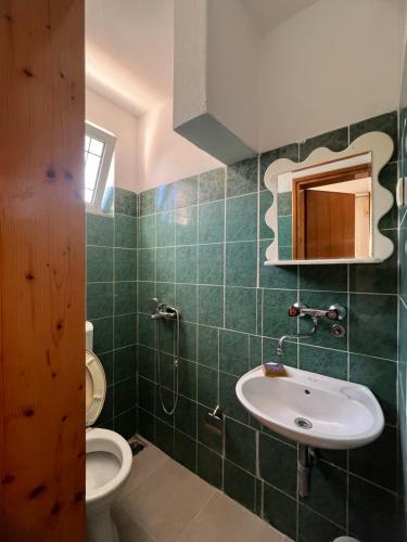 a green tiled bathroom with a sink and a toilet at Haus Binas in Ulcinj