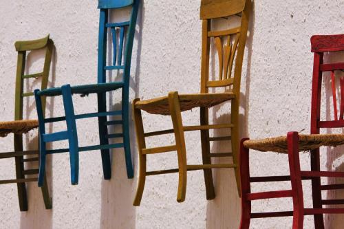 four different colored chairs hanging on a wall at Timbuktu Hostel in San Vito lo Capo