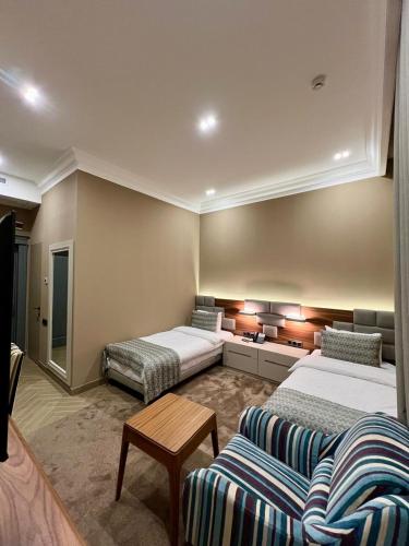 a hotel room with two beds and a couch at Plaza Viktoria Hotel Yerevan in Yerevan